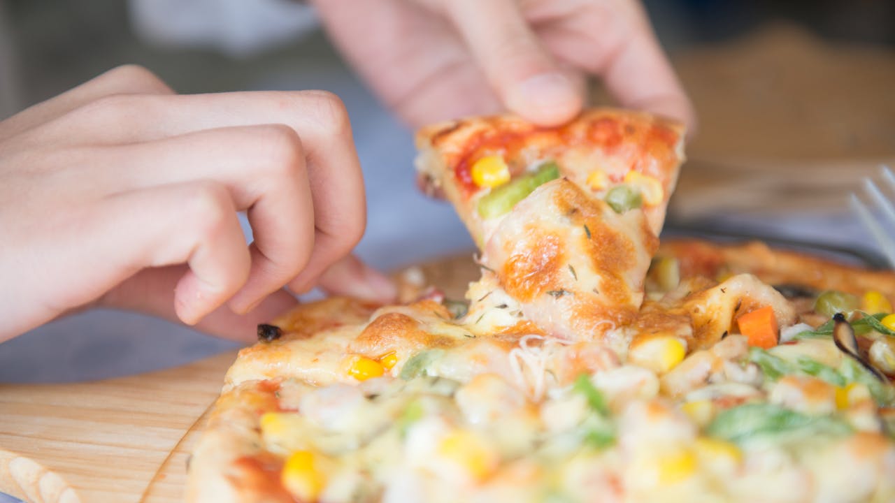 A delicious homemade veggie pizza being served with cheese and vegetable toppings.