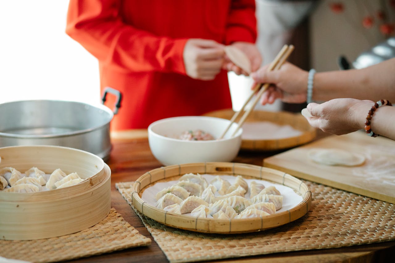 Home A group of people making homemade dumplings together in a cozy kitchen setting.